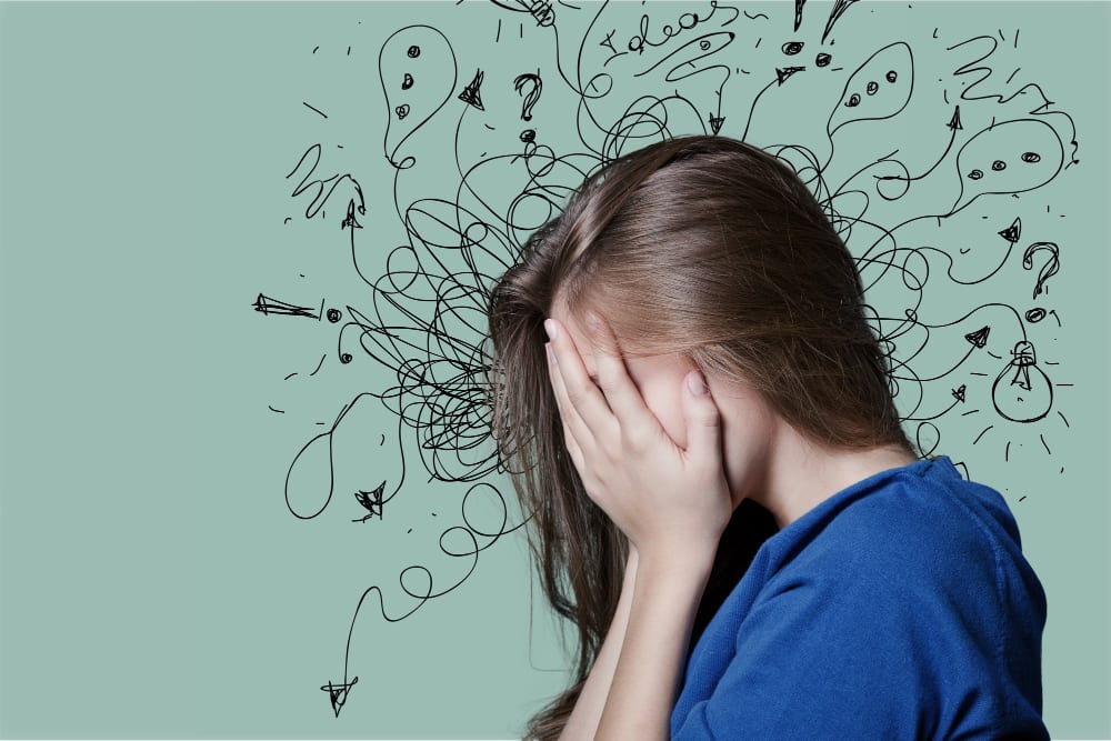 Femeie cu mâna la față pe fundal verde, înconjurată de linii încâlcite, semne de întrebare și becuri desenate